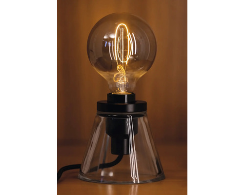 Lampe de table décorative avec une ampoule ronde sur un socle transparent.