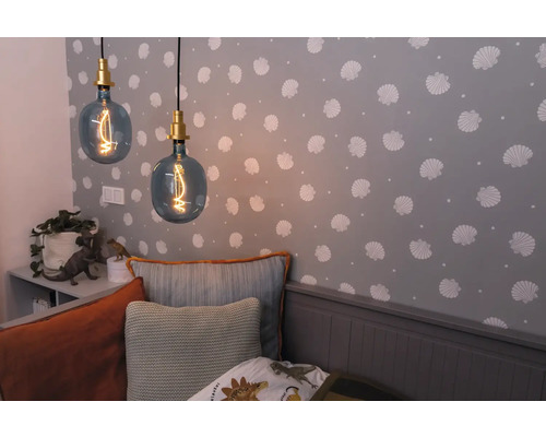 Zwei Pendelleuchten mit dekorativen Glühbirnen in einem Kinderzimmer mit Muscheltapete