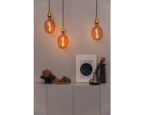 Scène décorative avec trois ampoules au-dessus d'un buffet avec des fruits, une citrouille et une image encadrée