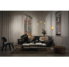 Wohnzimmer mit Sofa, Tisch, Leuchten und Vorhängen für eine gemütliche Atmosphäre.