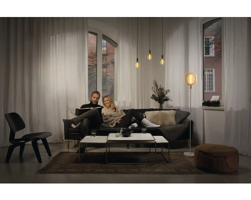 Wohnzimmer mit Sofa, Tisch, Leuchten und Vorhängen für eine gemütliche Atmosphäre.