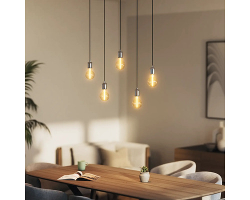 Fünfflammige Pendelleuchte über einem Esstisch mit Buch, Pflanze und Geschirr