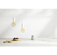 Zwei Pendelleuchten mit Glühbirnen hängen über einem Holztisch mit Schüssel und Krug.