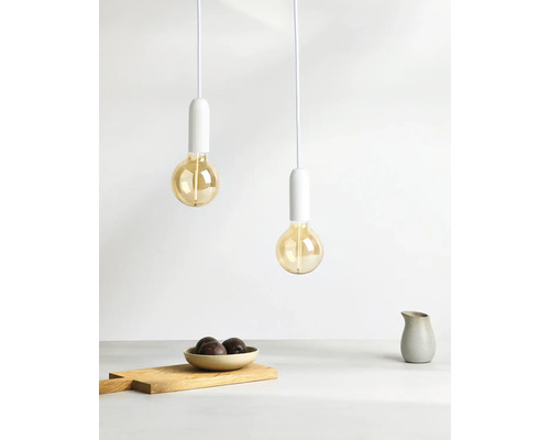 Zwei Pendelleuchten mit Glühbirnen über einem Tisch mit Schale, Schneidebrett und Krug.