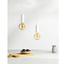 Zwei Pendelleuchten mit Glühbirnen über einer Tischszene mit Holzbrett und Schale