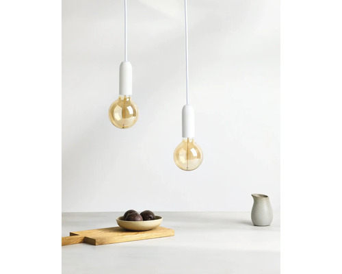 Zwei Pendelleuchten mit Glühbirnen über einer Tischszene mit Holzbrett und Schale