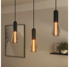 Trois suspensions avec douilles noires et ampoules Edison dans un intérieur.