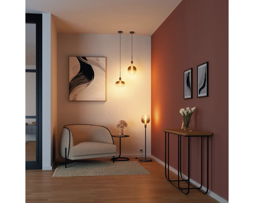 Salon avec fauteuil, table, lampadaire, suspensions et décorations