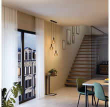 Modernes Interieur mit Pendelleuchte über einem Esstisch und einer Treppe im Hintergrund.