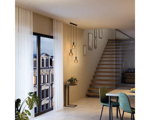 Modernes Interieur mit Pendelleuchte über einem Esstisch und einer Treppe im Hintergrund.