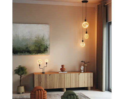 Wohnzimmer mit Holzkommode, Gemälde und dekorativer Beleuchtung durch Hänge- und Tischlampen.