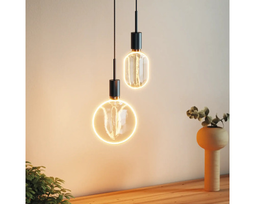 Zwei dekorative Pendelleuchten mit runden und ovalen Formen beleuchten einen Innenraum.