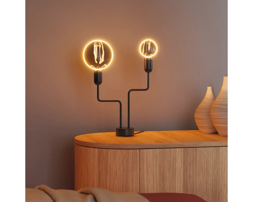 Dekorative Tischleuchte mit zwei Glühbirnen auf einem Holzschrank