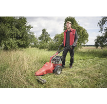 Un homme utilise une faucheuse à fléaux dans un champ