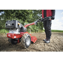 Motobineuse en utilisation dans un champ avec une personne qui la conduit