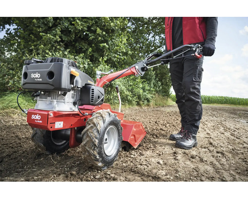 Motobineuse en utilisation dans un champ avec une personne qui la conduit