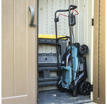 Ein Rasenmäher steht in einem Gartenschuppen.