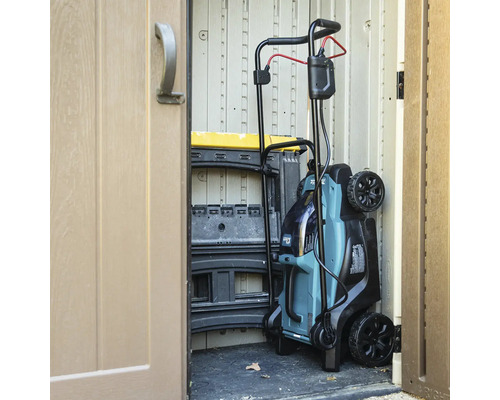 Ein Rasenmäher steht in einem Gartenschuppen.