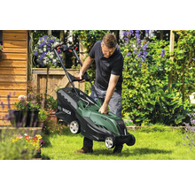 Mann hebt Rasenmäher im Garten an