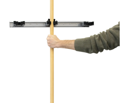 Un homme fixe un manche dans un support mural pour outils