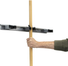 Une main insère un manche en bois dans un support d'outils.