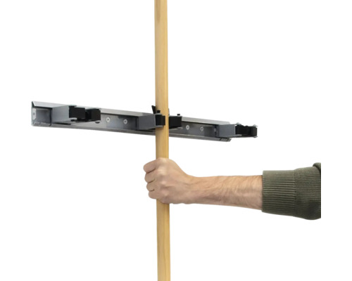 Une main insère un manche en bois dans un support d'outils.