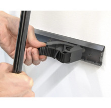 Une personne fixe un outil sur une barre porte-outils au mur.