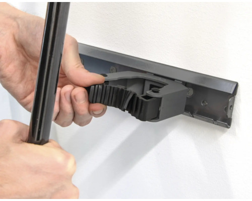 Une personne fixe un outil sur une barre porte-outils au mur.