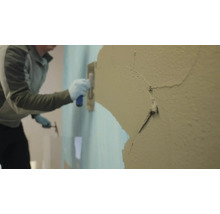 Un artisan applique du plâtre sur un mur.