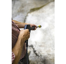 Une personne utilise un nettoyeur haute pression pour nettoyer une surface.