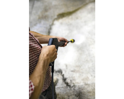 Une personne utilise un nettoyeur haute pression pour nettoyer une surface.