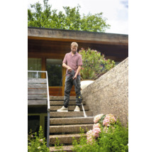 Un homme nettoie un escalier extérieur avec un nettoyeur haute pression.