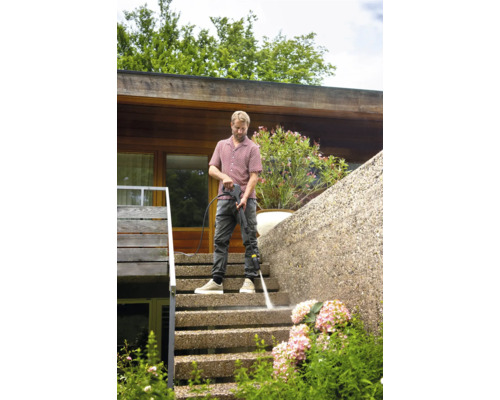 Un homme nettoie un escalier extérieur avec un nettoyeur haute pression.