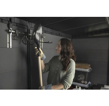 Femme tenant une pelle dans un abri de jardin avec système de suspension d'outils