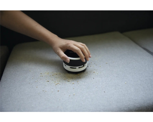 Tischstaubsauger wird zum Reinigen von Krümeln auf dem Sofa verwendet