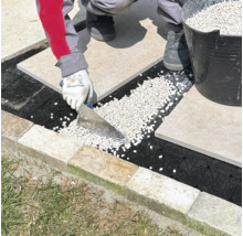Pose de dalles de terrasse sur un lit de gravier à l'aide d'une spatule.