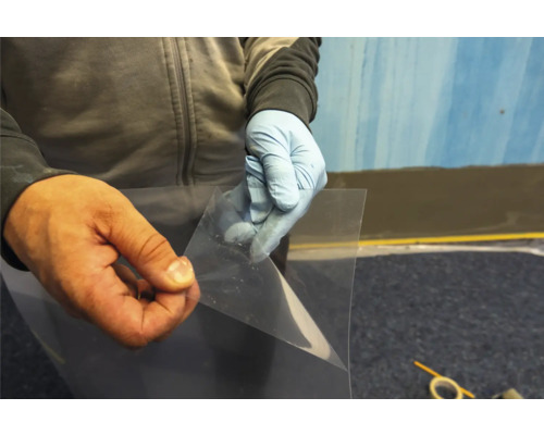 Une personne tient un film de protection transparent dans ses mains.