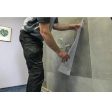 Artisan fixant un film transparent sur un mur