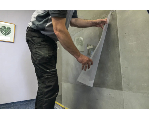 Artisan fixant un film transparent sur un mur