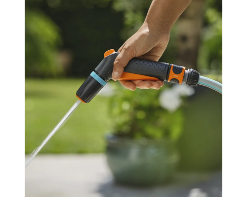 Une main tient un pulvérisateur de jardin d'où sort de l'eau.
