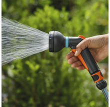 Une main tient un pistolet d'arrosage qui projette de l'eau.