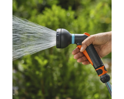 Une main tient un pistolet d'arrosage qui projette de l'eau.