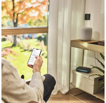 Personne avec smartphone pour contrôler l'arrosage du jardin dans le salon.