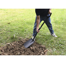 Une personne creuse dans le jardin avec une bêche.