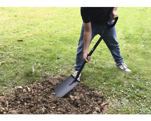 Une personne creuse dans le jardin avec une bêche.