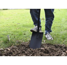 Une personne utilise une bêche dans le jardin pour retourner la terre.