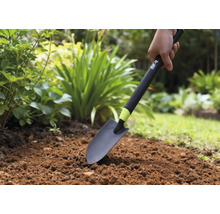 Person verwendet eine Gartenschaufel im Gartenbeet.