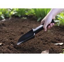 Une personne utilise une pelle à main dans le jardin.