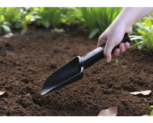 Une personne utilise une pelle à main dans le jardin.