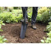Une personne utilise une bêche pour creuser dans le jardin.